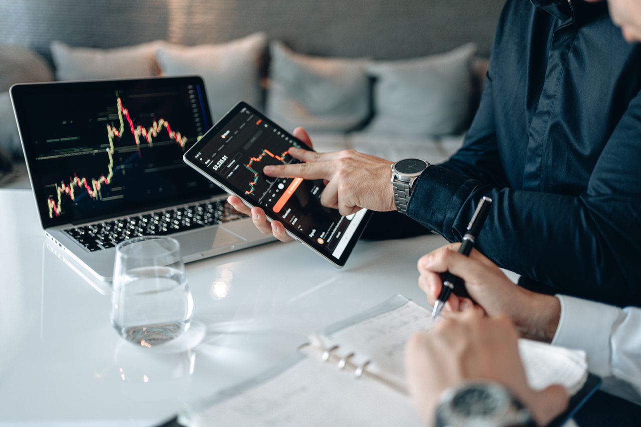 Services Professionals analyzing financial data on a tablet and laptop in an office setting.