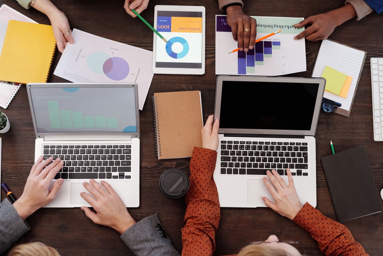 About Overhead view of a team discussing digital marketing strategies with laptops and charts.